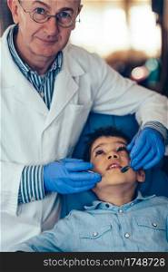 Dentist doing regular dental check-up to little boy.