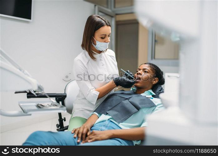 Dentist examines the teeth of female patient in dental clinic. Woman in dentistry cabinet, stomatology. Dentist examines the teeth, dental clinic