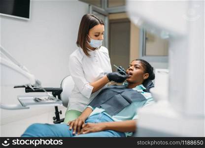 Dentist examines the teeth of female patient in dental clinic. Woman in dentistry cabinet, stomatology. Dentist examines the teeth, dental clinic