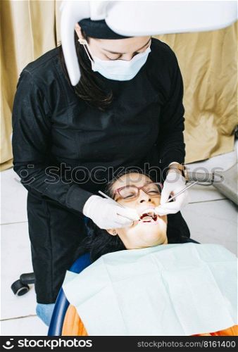 Dentist examining mouth to patient, Woman dentist doing endodontics to woman patient, Woman dentist with patient lying down, Dentist performing stomatology