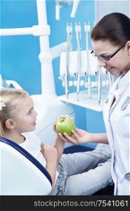 Dentist gives the patient a green apple