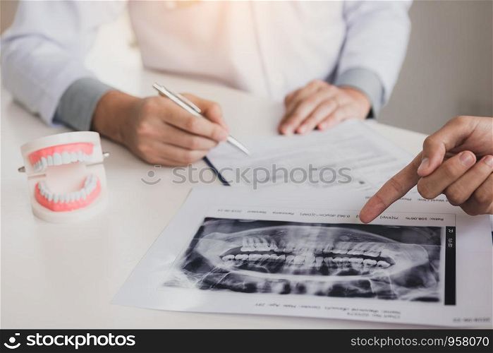Dentist hand holding pen and talking to the patient with pointing x-ray picture about medication and surgery treatment.