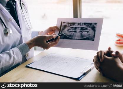 Dentist hand holding pen pointing x-ray picture and talking to the patient about medication and surgery treatment.