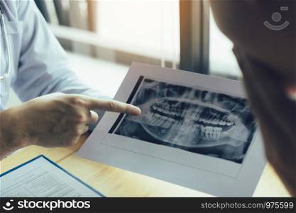Dentist hand pointing x-ray picture and talking to the patient about medication and surgery treatment.