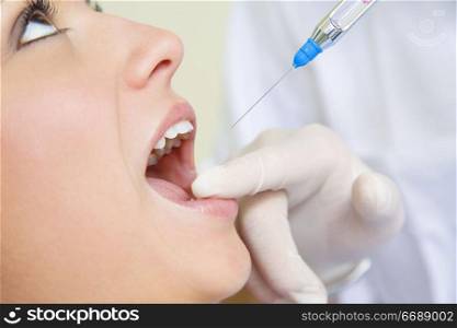 dentist holding a syringe and anesthetizing his patient. Close-up of mouth open