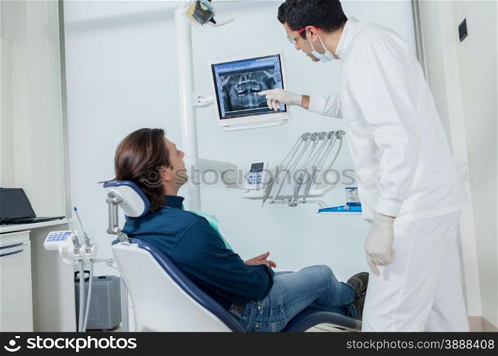Dentist is showing his patient on the monitor what he is going to do