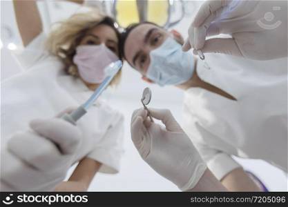 Dentist leaned over patient in dentist&rsquo;s chair at clinic. Doctor with mask and tools.