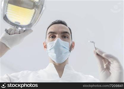 Dentist leaned over patient in dentist&rsquo;s chair at clinic. Doctor with mask and tools.