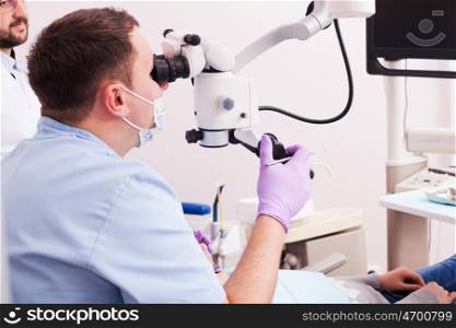 Dentist looking through magnifying glass. He's using microscope for operation at dentist office