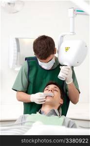 Dentist preparing x-ray machine on young male patient