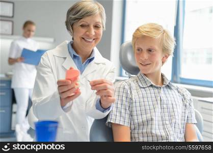 Dentist show teenage patient teeth dentures assistant at dental clinic