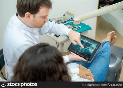Dentist showing teeth x-ray on digital tablet screen,Dental consultation in dentist office,people, medicine, stomatology and health care concept.