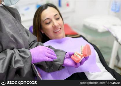 Dentist showing to patient an orthodontics dental model, explaining to patient the orthodontics treatment in dental clinic. High quality photo. Dentist showing to patient an orthodontics dental model, explaining to patient the orthodontics treatment in dental clinic.