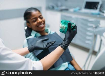 Dentist shows dentures to female patient in dental clinic, professional prosthetic dentistry, stomatology care cabinet. Dentist shows dentures to patient in dental clinic