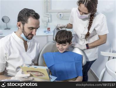 Dentist shows structure of the tooth to little boy. Male Dentist shows structure of the tooth to little boy