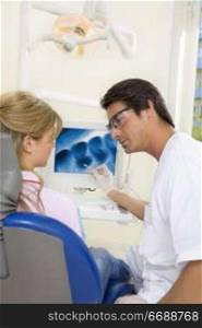 dentist talking to his patient and showing her a x-ray image of her teeth