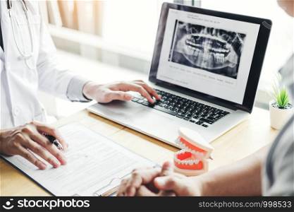 Dentist talking to male patient and presenting results on Dental x-ray film About the problem of the patient in dental office
