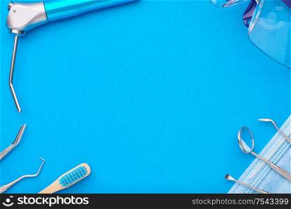 Dentist tools over blue background top view copy space flat lay. Tooth care, dental hygiene and health concept.