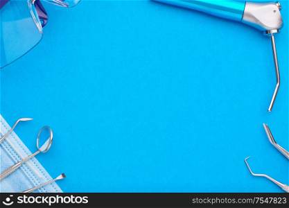 Dentist tools over blue background top view copy space flat lay. Tooth care, dental hygiene and health concept.