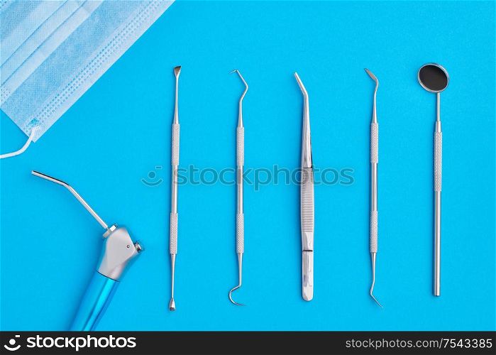 Dentist tools over blue background top view flat lay. Tooth care, dental hygiene and health concept.
