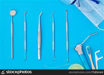 Dentist tools over blue background top view flat lay. Tooth care, dental hygiene and health concept.