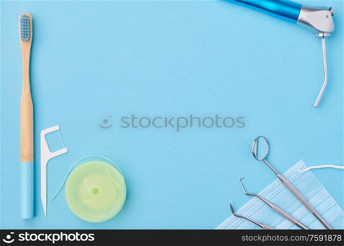 Dentist tools over light blue background top view copy space flat lay. Tooth care, dental hygiene and health concept.