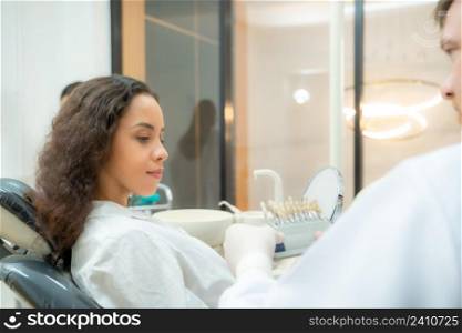 Dentist using dental equipment for examination of teeth of a female patient,Compare teeth with sampler in dentistry.