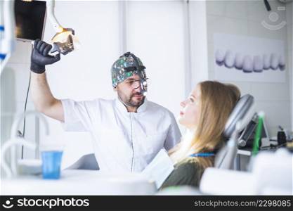 dentist wearing dental loupe binoculars treating female patient