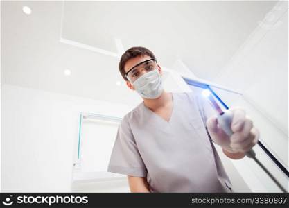 Dentist wearing mask holding UV light