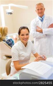Dentist with assistant smiling at stomatology office professional health care