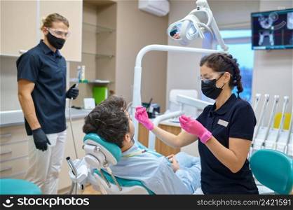 Dentist with assistant treating patient teeth. Man having tooth examination at dental consultation. Patient having teeth examination at dental consultation