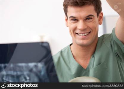 Dentist with xray in hand, smiling at the camera