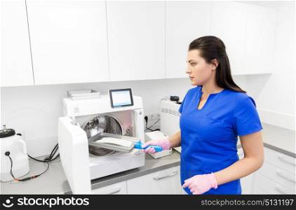 dentistry, medicine and healthcare concept - female dentist assistant arranging sterilization or disinfection of tools at dental clinic. dentist sterilizing tools at dental clinic. dentist sterilizing tools at dental clinic