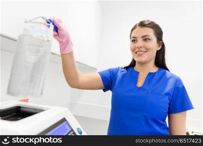 dentistry, medicine and healthcare concept - female dentist assistant arranging sterilization or disinfection of tools at dental clinic. dentist sterilizing tools at dental clinic. dentist sterilizing tools at dental clinic