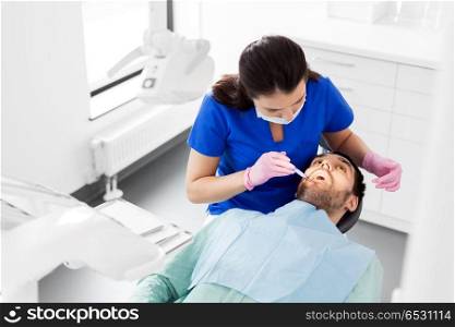 dentistry, medicine and healthcare concept - female dentist with mouth mirror checking up male patient teeth at dental clinic office. female dentist checking up male patient teeth. female dentist checking up male patient teeth