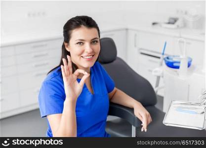 dentistry, medicine and healthcare concept - smiling female dentist or nurse at dental clinic office showing ok hand sign. dentist at dental clinic showing ok hand sign. dentist at dental clinic showing ok hand sign