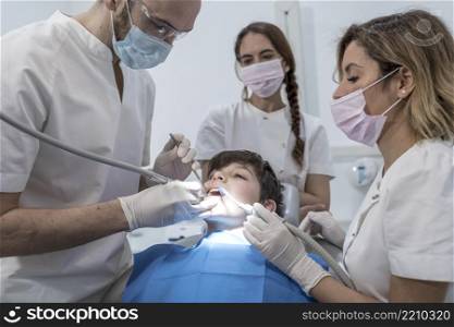 Dentists examining little boy&rsquo;s teeth in clinic