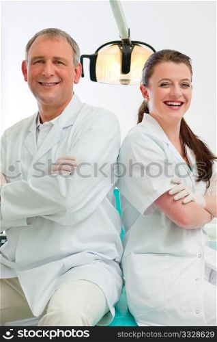 Dentists in their surgery looking at the viewer standing side by side