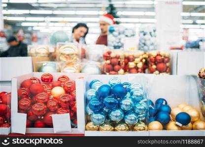 Department of holiday decorations in supermarket, family tradition. December purchasing of new year or christmas goods. Couple shopping, department of holiday decorations