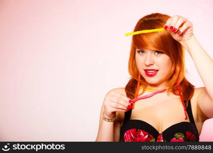 Dependence on sweets. Young red haired woman with candy on pink bacground in studio.