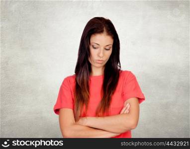 Depressed brunette girl dressed in red on a gray background