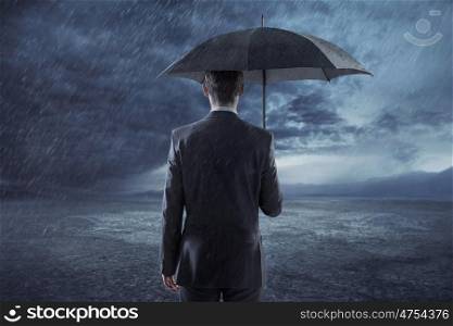 Depressed businessman standing with an umbrella