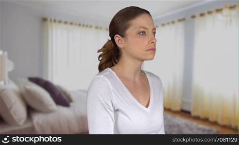 Depressed female stares into distance in bedroom