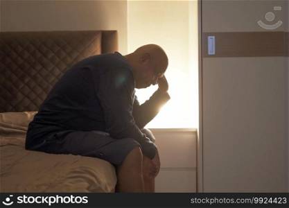 Depressed lonely old elderly black man. African American people sitting on bed in bedroom at home. Lifestyle on late night. Insomnia. Quarantine