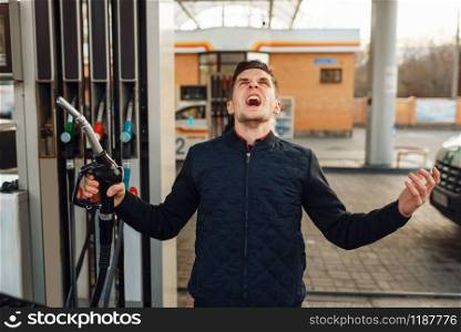 Depressed man cries on gas station, high price on fuel. Petrol fueling, gasoline or diesel refuel service, petroleum refueling. Depressed man cries on gas station, fuel filling