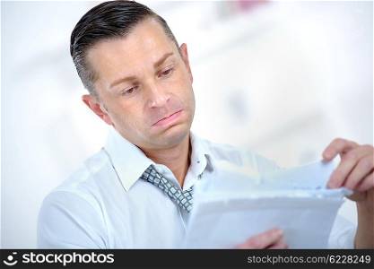 Depressed man looking at paperwork