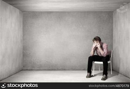 Depressed man sitting on a chair all alone. Being in despair