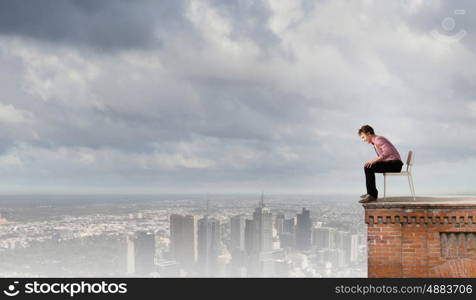 Depressed man sitting on a chair all alone. Being in despair