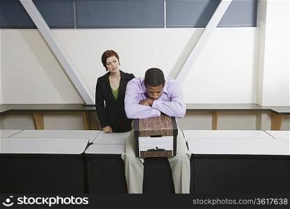 Depressed Man Sitting on Desk with Moving Box