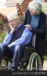 Depressed Senior Man In Wheelchair Being Pushed By Wife